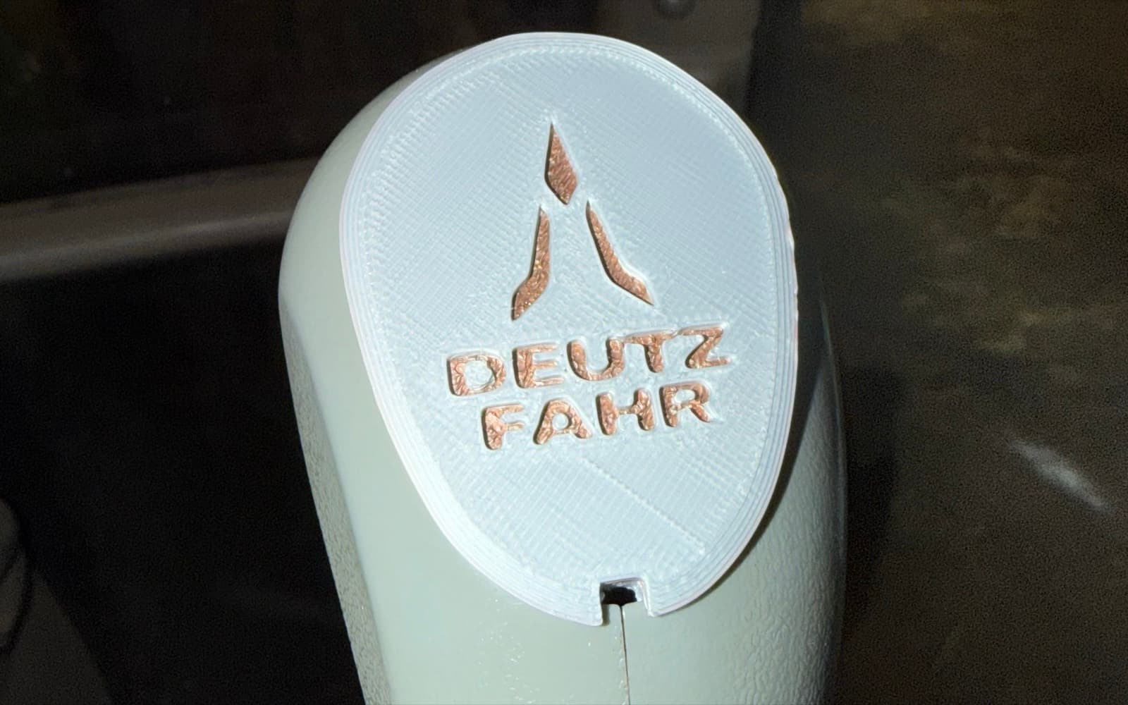 Hvitt 3D-printet deksel på joystick i frontlaster, med preget Deutz-Fahr-logo og fargeaksent i graveringen